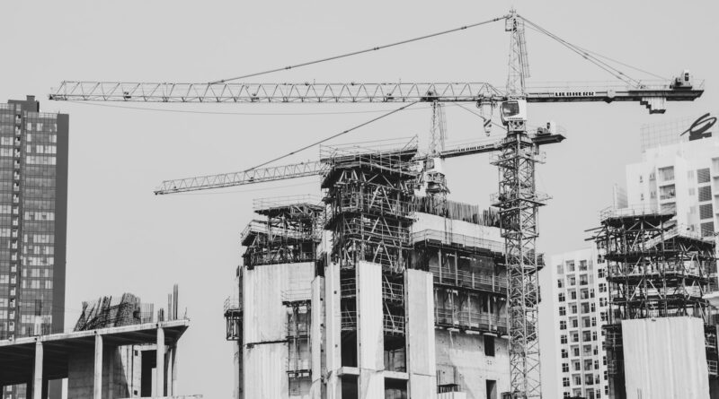 grayscale photo of building with tower crane